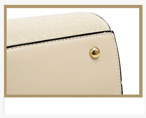 Gros plan sur le cuir crème à motif crocodile avec rivet doré et coutures noires précises