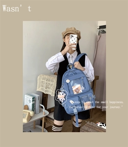 Détail d'un sac à dos scolaire bleu clair avec plusieurs poches et pendentif vache