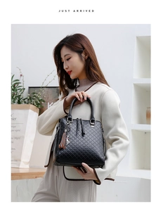 Détail du sac à main en cuir matelassé noir avec pendentif chat argenté et accessoire gland