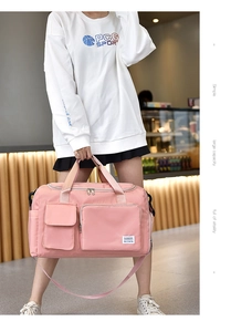 Detail view of pink waterproof travel bag showing front zipper pockets and sturdy handles