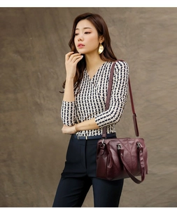 Detail view of burgundy pebble leather shoulder bag with V-shaped stitching and dual handles