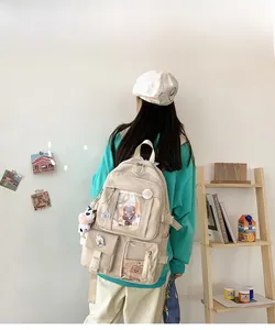 Détail d'un sac à dos en nylon beige avec plusieurs poches transparentes et breloques