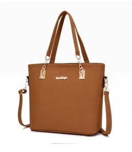 Detail view of brown faux leather tote bag with fine texture and gold hardware accents
