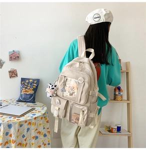 Détail du sac à dos scolaire en nylon crème avec plusieurs poches et pendentif panda