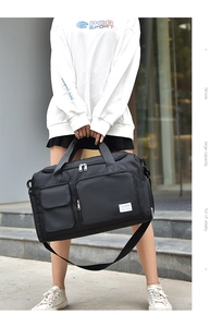 Detail view of black waterproof nylon travel bag with multiple pockets and reinforced handles