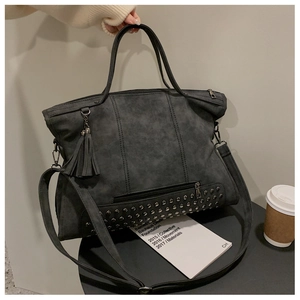 Close-up of charcoal grey tote bag featuring fringe charm and metal rivet details