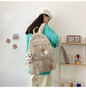 Détail d'un sac à dos en toile crème avec plusieurs poches et pendentif vache en peluche