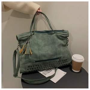 Detail of dark green vintage tote bag with metal studs, tassels and adjustable shoulder strap