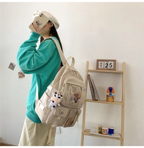 Détail d'un sac à dos en toile beige avec des pendentifs mignons et plusieurs poches