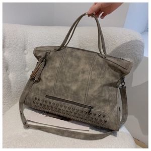 Detail of vintage grey tote bag featuring metal rivets, fringe tassel, and durable handles