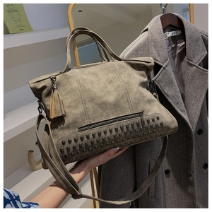 Detail of rivet and tassel elements on large vintage taupe suede shoulder bag for women