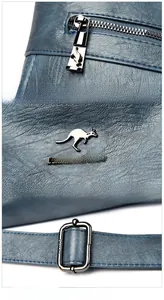 Detalle de mochila de cuero granulado con herrajes plateados y logo de canguro metálico