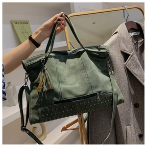 Detail of vintage green tote bag featuring fringe charm and rivet studs on suede texture