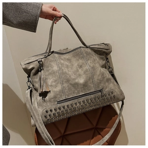 Detail of grey vintage tote bag showing rivet studs, leather tassel and matte texture