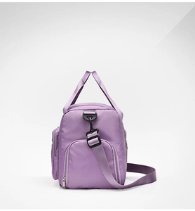 Detail view of the purple waterproof travel bag showing side zipper and adjustable strap