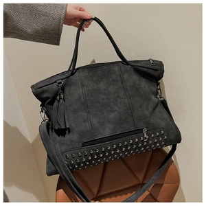 Detail of black rivet tote bag with tassel and vintage studs in a home setting