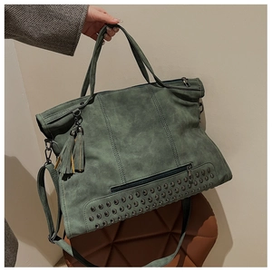 Detail of dark green tote bag featuring rivet studs and decorative double tassels