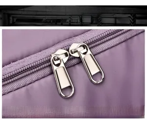 Detail of smooth double zipper closure on purple waterproof nylon travel bag with silver metal pulls