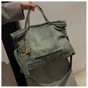 Detail of grey-green suede tote bag featuring metallic rivets and stylish side tassel