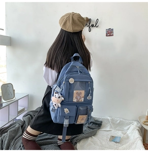 Vue arrière du sac à dos scolaire en nylon bleu avec poches et breloques mignonnes
