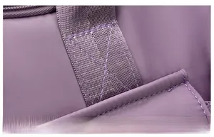 Detail of reinforced X-shaped stitching on purple waterproof travel bag handle for durability