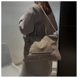 Detail view of vintage coffee brown tote bag featuring rivet studs and tassel charm