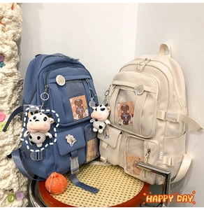 Détail de grands sacs à dos scolaires bleu et beige avec breloques et poches multiples