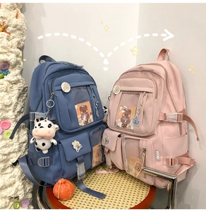 Détail de sacs à dos bleu et rose avec plusieurs poches, fente PVC et breloques mignonnes