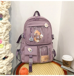 Détail d'un sac à dos violet multi-poches avec des badges de dessin animé et accessoires