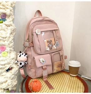 Gros plan d'un sac à dos rose avec plusieurs poches, fenêtre transparente et breloques