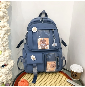 Vue détaillée du sac à dos bleu marine multi-poches avec pendentif ours et badges