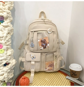 Détail du sac à dos oxford crème avec fenêtres transparentes et breloques d'ours