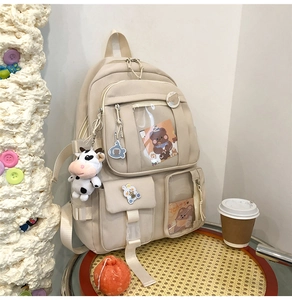 Détail d'un sac à dos en nylon crème avec poches multiples et accessoires mignons