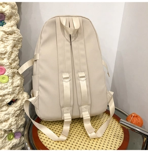Détail des bretelles rembourrées ajustables et de la poignée sur le sac à dos blanc cassé