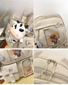 Vue détaillée du sac à dos en toile crème avec pendentif vache et badges ours