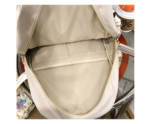 Vue détaillée de l'intérieur du sac à dos beige avec doubles poches et compartiment large