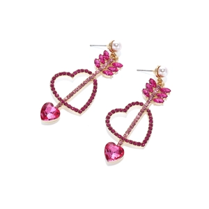 Détail de boucles d'oreilles cœur en cristal rose avec flèche de Cupidon et perles