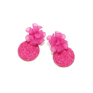 Detailed macro view of woven raffia circle and matte resin flower petals on earrings