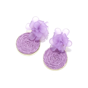 Detailed view of handmade purple resin flower earrings with woven raffia disc accents