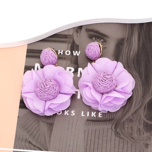 Detailed view of handmade purple chiffon flower earrings with raffia woven accents