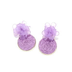 Detail view of purple resin flower earrings with woven raffia texture and gold metal rim
