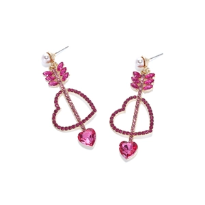 Détail macro de boucles d'oreilles cœur fléché avec strass roses et petite perle blanche