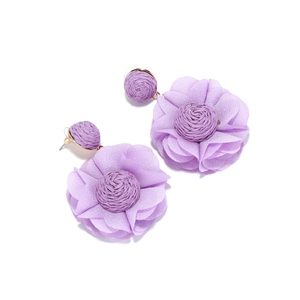 Detailed view of handmade purple chiffon flower earrings with raffia woven studs