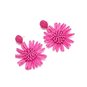 Détail des boucles d'oreilles tournesol en raphia rose avec texture tissée à la main