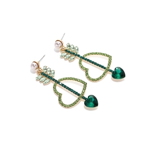 Détail de boucles d'oreilles cœur en cristal vert avec flèche et perle blanche