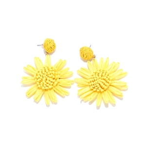 Gros plan de boucles d'oreilles tournesol en raphia jaune avec texture tissée à la main