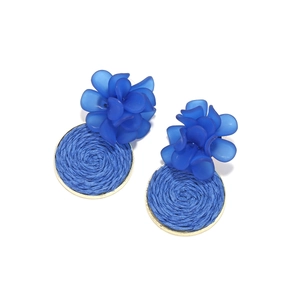 Close-up of blue resin flower earrings with handmade woven straw raffia circles