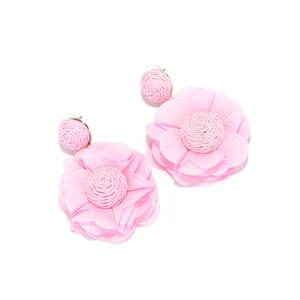 Macro shot of pink chiffon fabric flower earrings with woven raffia centers on white background