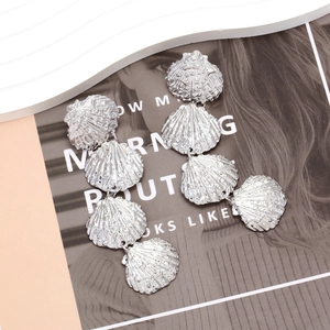 Detail showing multi-layer silver shell earrings with textured metallic finish