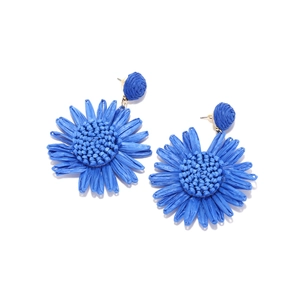 Gros plan détaillé de boucles d'oreilles tournesol en raphia bleu tissé main